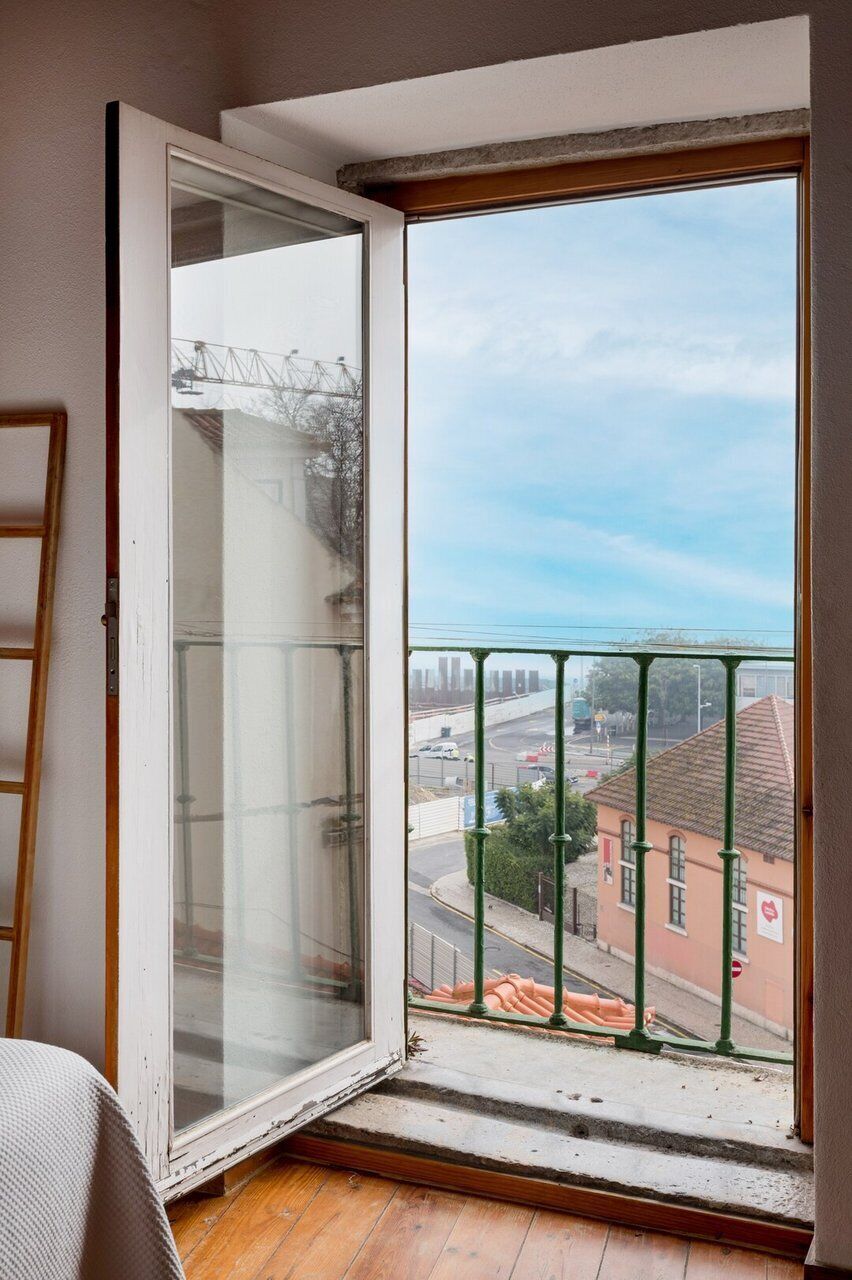 A room with a large window, a wooden floor, and a view of a cityscape.