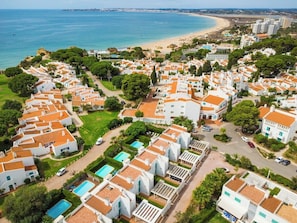 A coastal residential area with white buildings, swimming pools, and a beach in the background. - Sunny 5BR Villa @ Prainha Club (Alvor)
