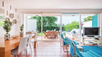 Un grand espace de vie comprenant une table à manger, des chaises, un canapé et un téléviseur.