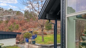 A modern house with a stone pathway leading to a covered area with potted plants.