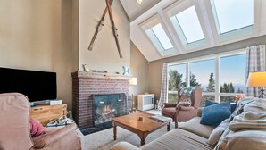 A living room with a fireplace, a sofa, a coffee table, and a television. - Saddleback | 14 Clubhouse | Ski in/out | Sauna (Rangeley)