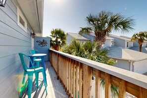 A wooden deck with a railing, a turquoise chair, and a table. - Feelin Beachy, Shared Pool, Walk to the Beach (Port Aransas)