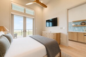 A bedroom with a bed, a TV, a dresser, and a view of the outdoors. - SBSL724 Ocean View, Private Heated Pool, Golf Cart Included, Boardwalk to the Beach (Port Aransas)