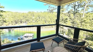 A covered outdoor area with a view of a lake and trees, featuring wicker chairs and a small table. - 5BR Lakefront Retreat — Quiet Cove, Large Private Dock & Easy Boat Access (Bremen)