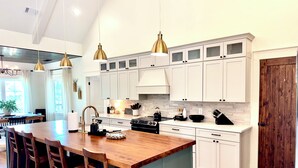 A modern kitchen with white cabinets, a wooden island, and pendant lighting. - 5BR Lakefront Retreat — Quiet Cove, Large Private Dock & Easy Boat Access (Bremen)