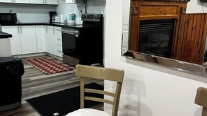 A modern kitchen with white cabinets, a black stove, and a microwave. There is a wooden chair and a rug on the floor. - Prime Location 3Bedrooms, 2 Bath,Basement Apt with free parking-Close to Transit (Mississauga)