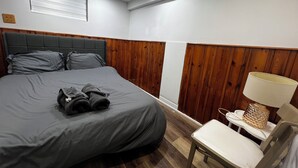 A bedroom with a bed, a chair, a lamp, and wooden paneling on the walls. - Prime Location 3Bedrooms, 2 Bath,Basement Apt with free parking-Close to Transit (Mississauga)