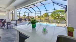 Un espace piscine intérieur moderne doté d’un toit en verre, d’une table de billard et d’un coin salon extérieur.