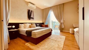 Camera moderna con un letto grande, un comodino, un tavolino e un condizionatore d'aria a parete, con vista sull'esterno tramite un'ampia finestra.