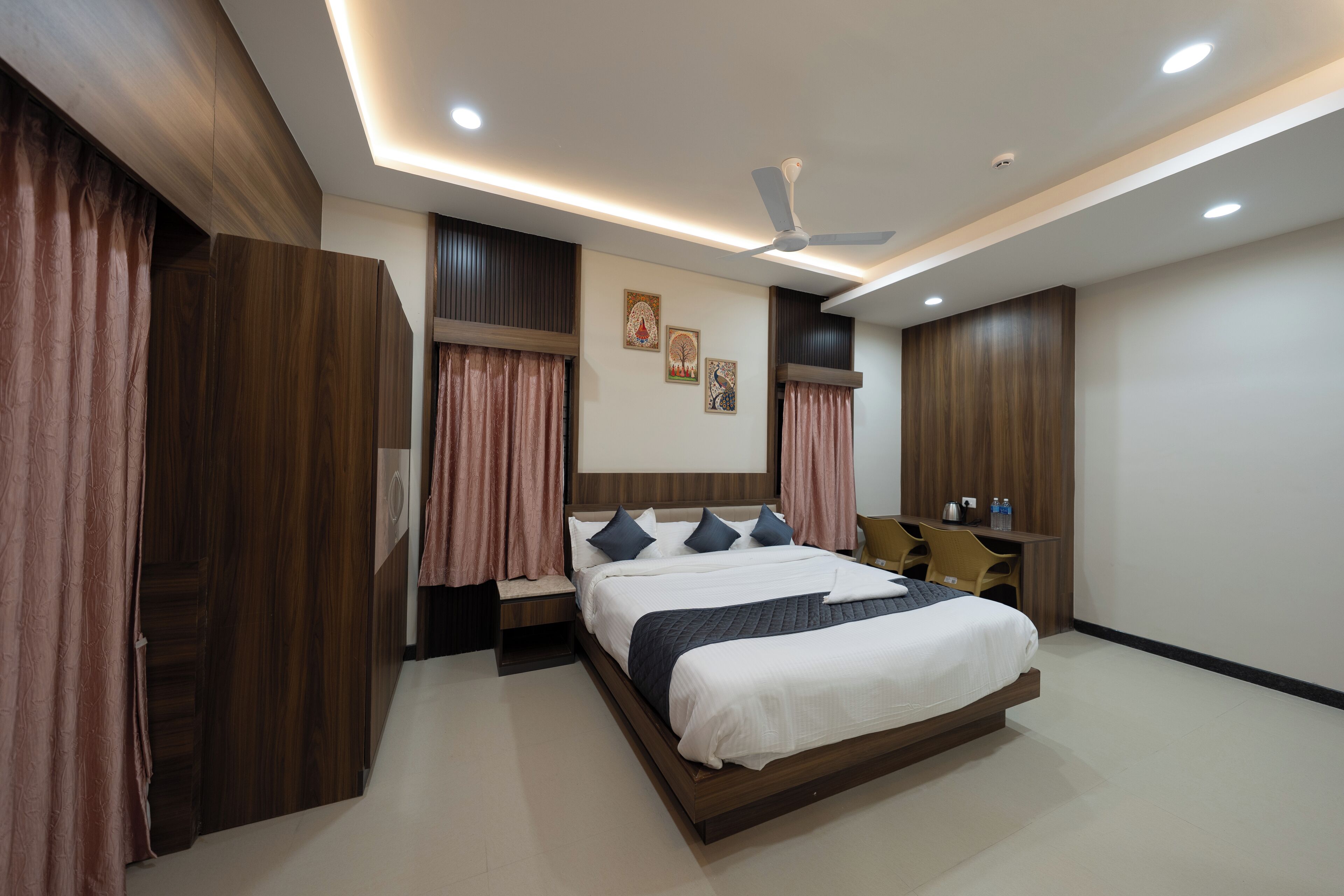 Un dormitorio moderno con una cama grande, ventilador de techo, iluminación empotrada y paneles de madera.