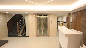 Un área de recepción moderna con escalera, ascensor y mostrador de recepción.