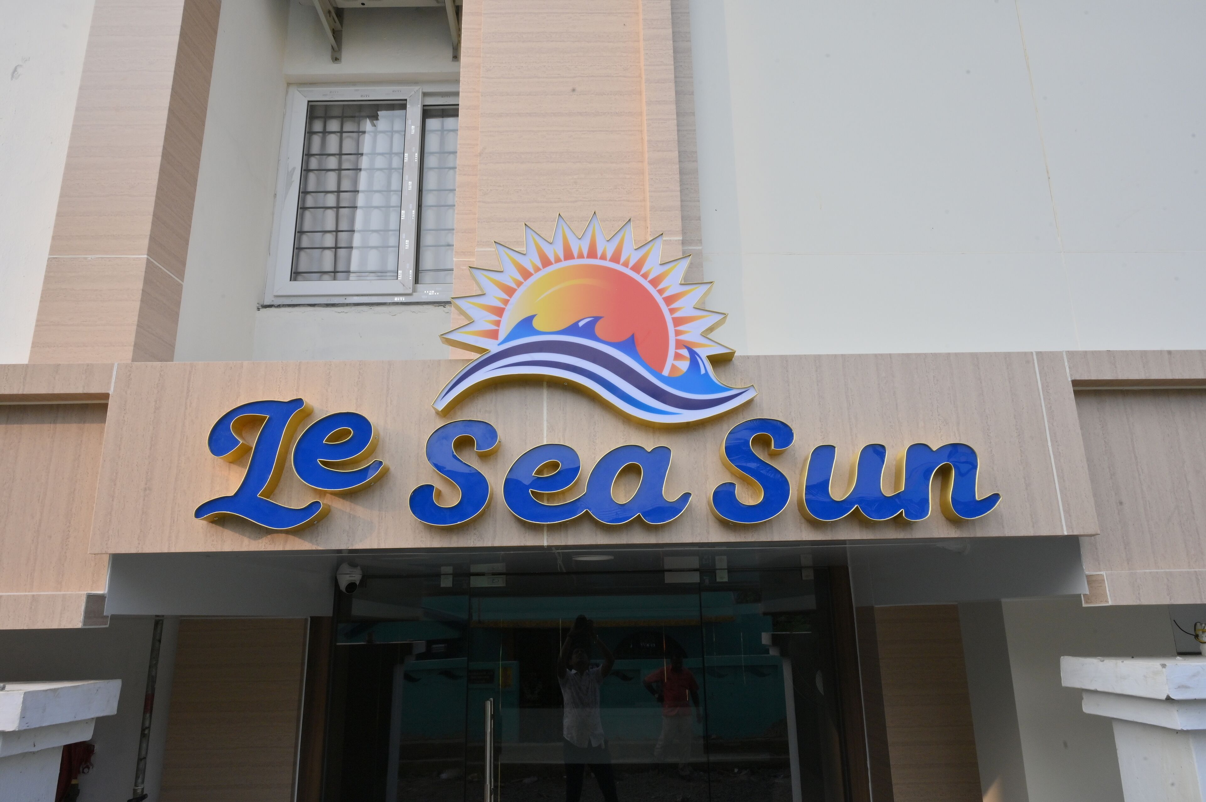 A hotel sign with a sun and wave logo, indicating a seaside theme.
