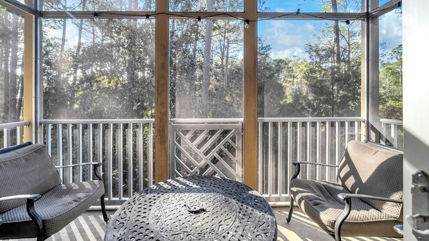 Un espace extérieur abrité, avec une table en métal et deux chaises, donnant sur une zone boisée.
