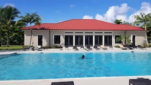 A swimming pool with lounge chairs and a building with a red roof.