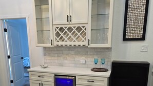 Una cocina con armarios blancos, lavavajillas y una campana extractora negra.