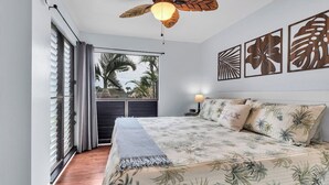 A bedroom with a bed, a ceiling fan, a window with curtains, and wall art. - #57 Beautifully Remodeled Studio (Pahala)