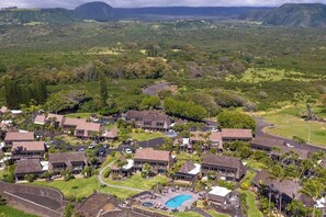 Un resort con varias edificaciones, piscina y abundante vegetación.