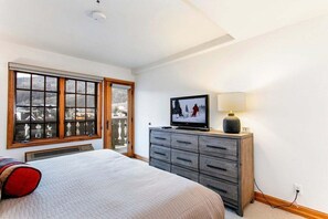 A bedroom with a large window, a bed, a dresser, and a television. - Ski In/Out at Gondola One Vail Slopeside Lodge 401 (Vail)