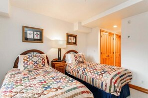 A room with two beds, a nightstand, a lamp, and framed pictures on the wall. - Ski In/Out at Gondola One Vail Slopeside Lodge 401 (Vail)