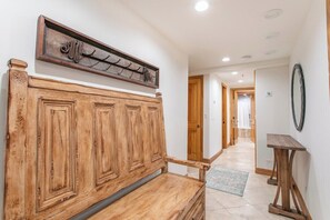 A hallway with a wooden bench, a coat rack, and a small table. - Ski In/Out at Gondola One Vail Slopeside Lodge 401 (Vail)