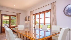 Una sala de conferències amb taula de vidre, cadires blanques, finestres grans i un rellotge a la paret.