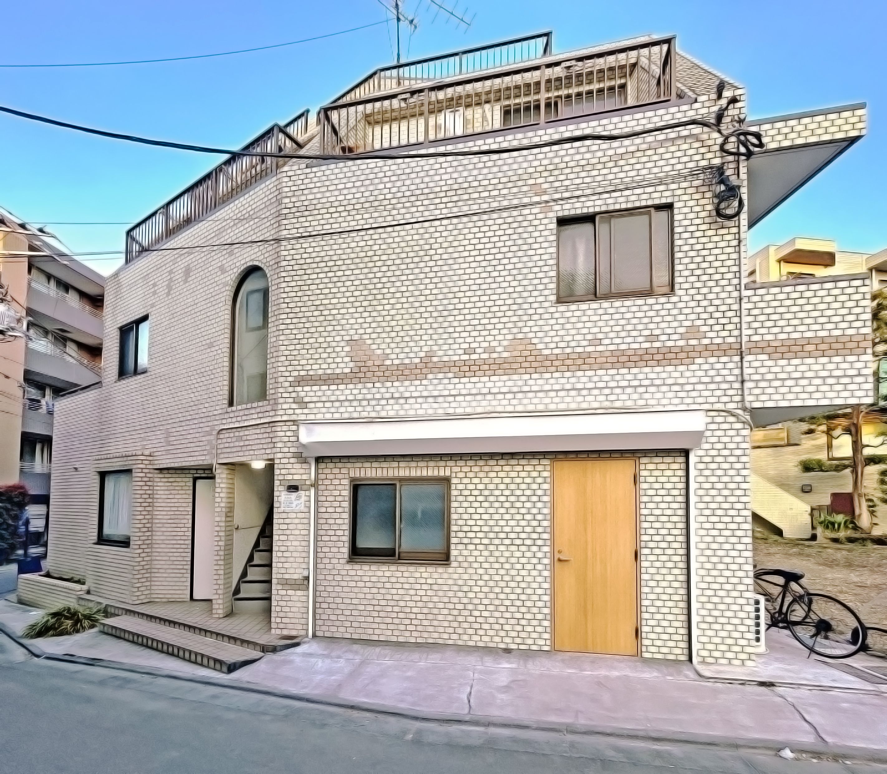 A two-story building with a brick facade, a wooden door, and a small balcony.