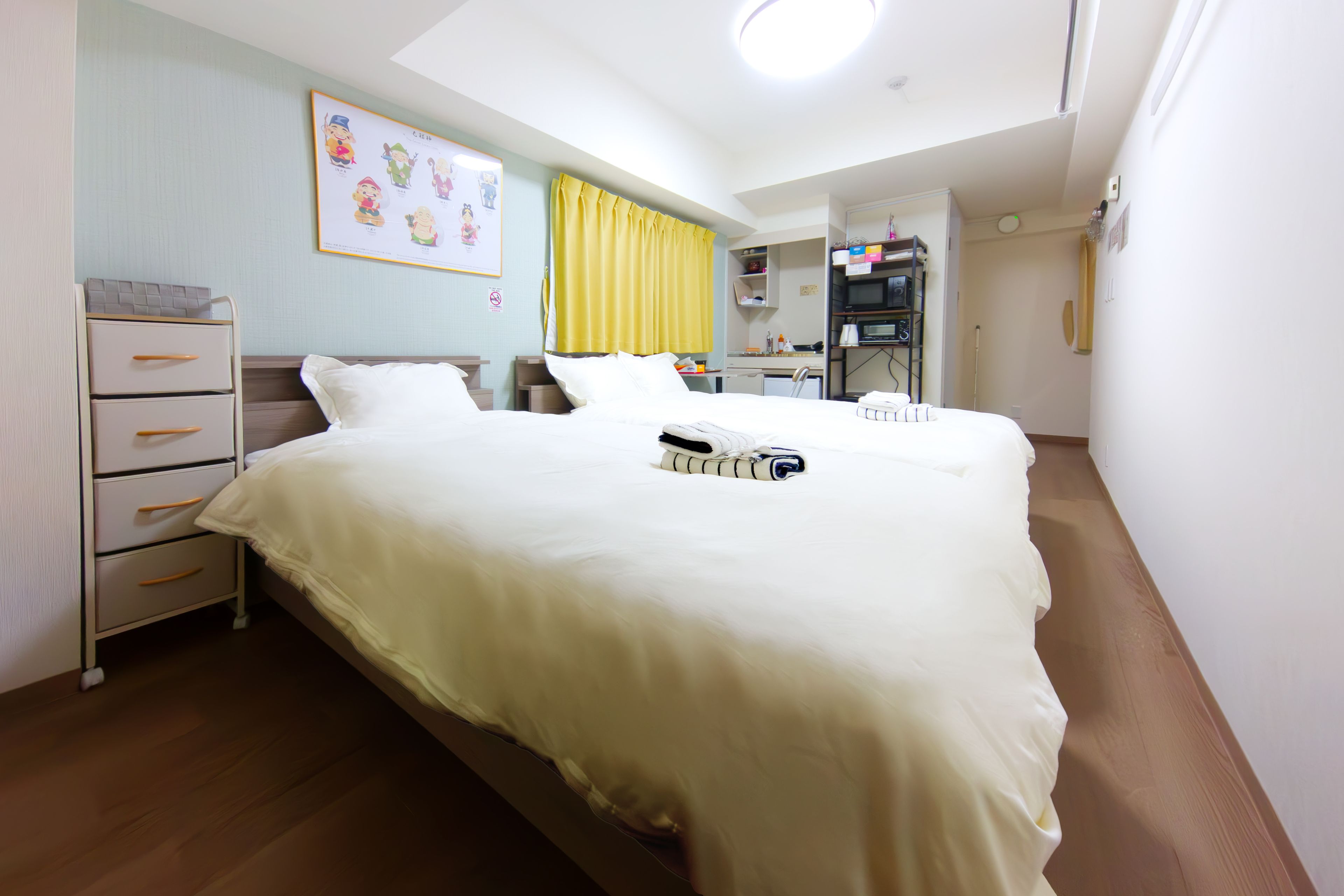 A hotel room with a bed, bedside tables, a desk, a chair, a wardrobe, and a bathroom.