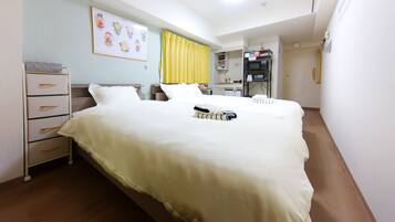 A hotel room with a bed, bedside tables, a desk, a chair, a wardrobe, and a bathroom.