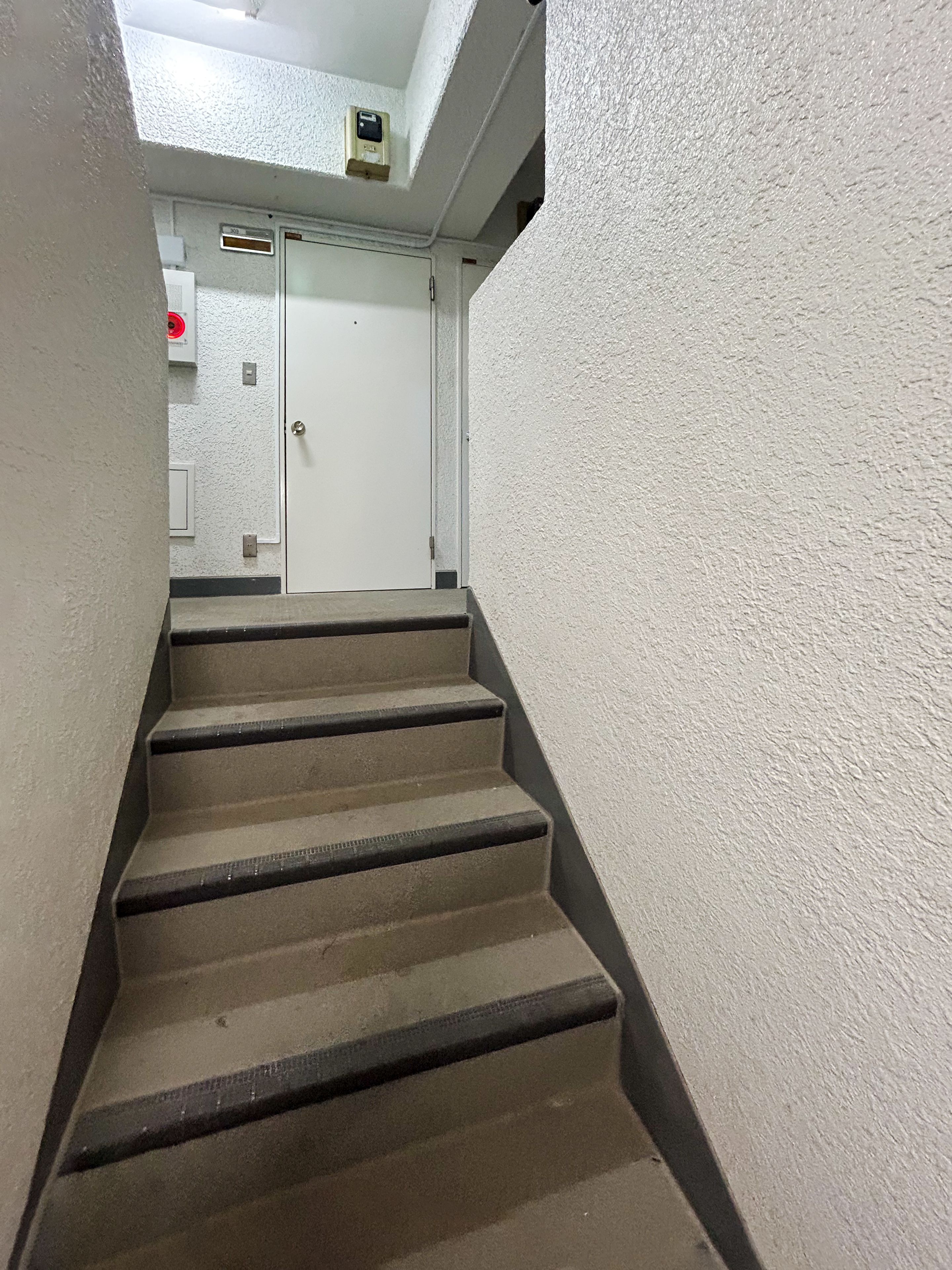 A staircase with a handrail leading to a door at the top.