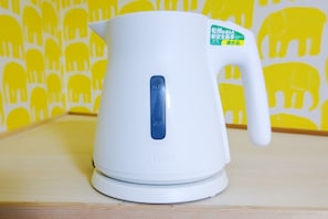 A white electric kettle with a blue button on a wooden surface. - Ikebukuro 5 Min by Train | 21㎡ for 3 | Double + Single Bed, Kitchen | Wi-Fi (板橋区)