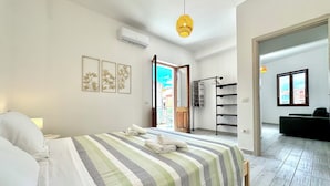 Una camera da letto con un letto, un lampadario, un condizionatore d'aria a parete e vista sull'esterno.