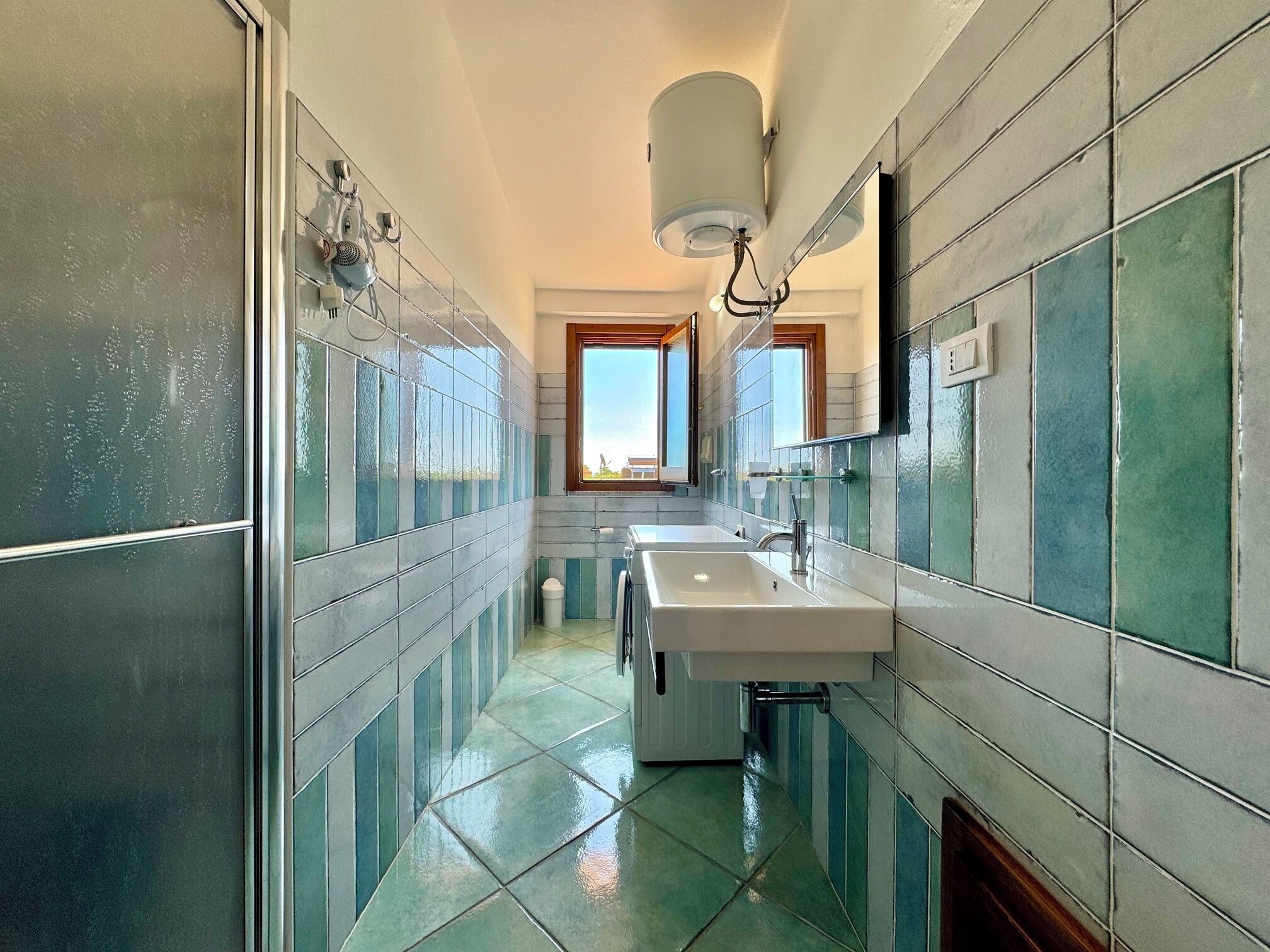 Une salle de bain avec un grand miroir, deux lavabos et une douche.