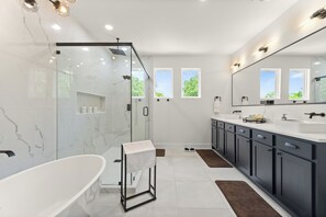 A modern bathroom with a glass-enclosed shower, a freestanding bathtub, and a large mirror. - Spacious 5-bedroom house in lovely Dallas near airport and downtown. (Dallas)