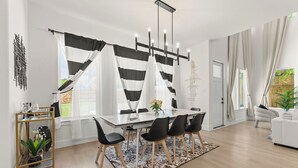 A modern dining area with a glass table, black chairs, and a patterned rug.