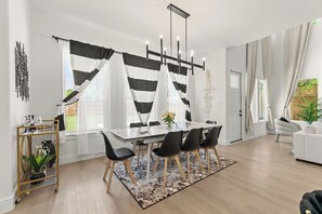 A modern dining area with a glass table, black chairs, and a striped curtain. - Spacious 5-bedroom house in lovely Dallas near airport and downtown. (Dallas)