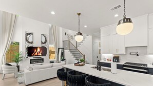 A modern kitchen with white cabinets, a central island, and a dining area with black bar stools.