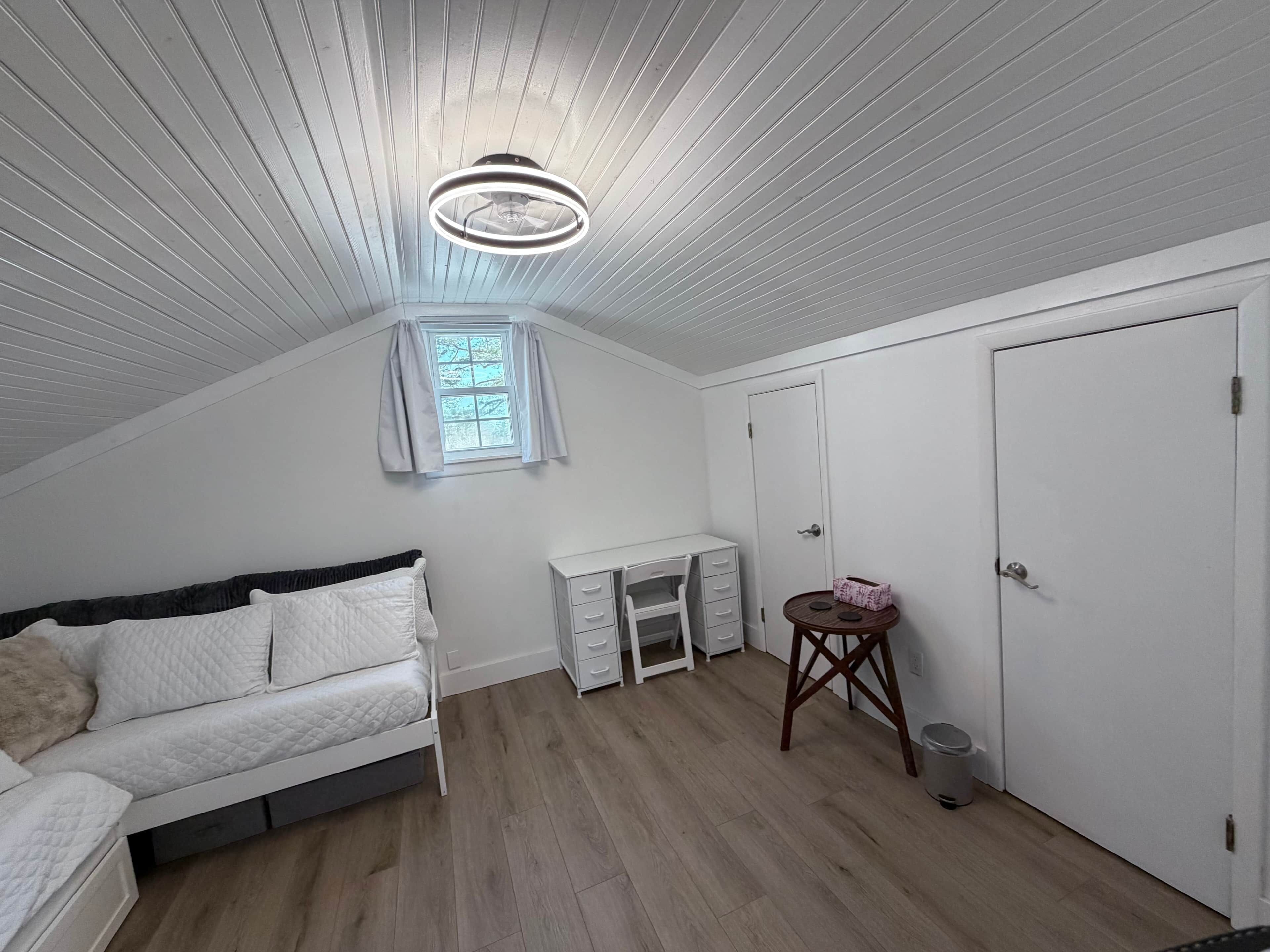 A bedroom with a bed, a desk, a wardrobe, and a window with curtains.
