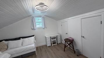 A bedroom with a bed, a desk, a wardrobe, and a window with curtains.