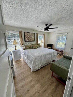 A bedroom with a bed, bedside tables, a chair, a ceiling fan, and windows with blinds. - Work/Family Groups: Huge Living Room+Fun Backyard (Mantachie)