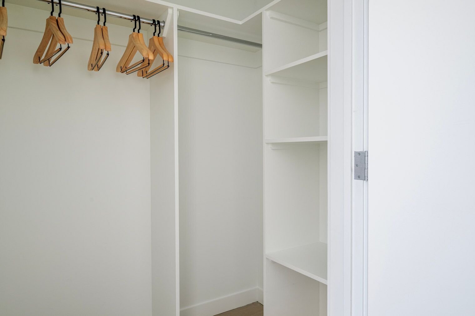 Un vestidor amplio con perchas de madera y estantes.