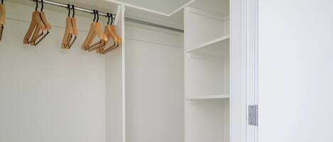 Un vestidor amplio con perchas de madera y estantes.