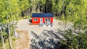 Une cabane rouge avec une terrasse, entourée d’arbres.