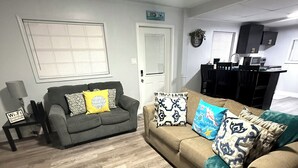 A living room with two couches, a dining table, and a kitchen area in the background. - Relaxing 1-bedroom Apartment in beautiful Ormond Beach (Ormond Beach)