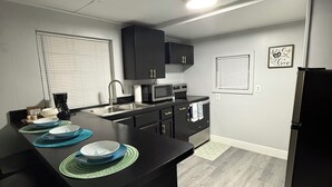 A modern kitchen with black countertops, a central island, and a black refrigerator. - Relaxing 1-bedroom Apartment in beautiful Ormond Beach (Ormond Beach)