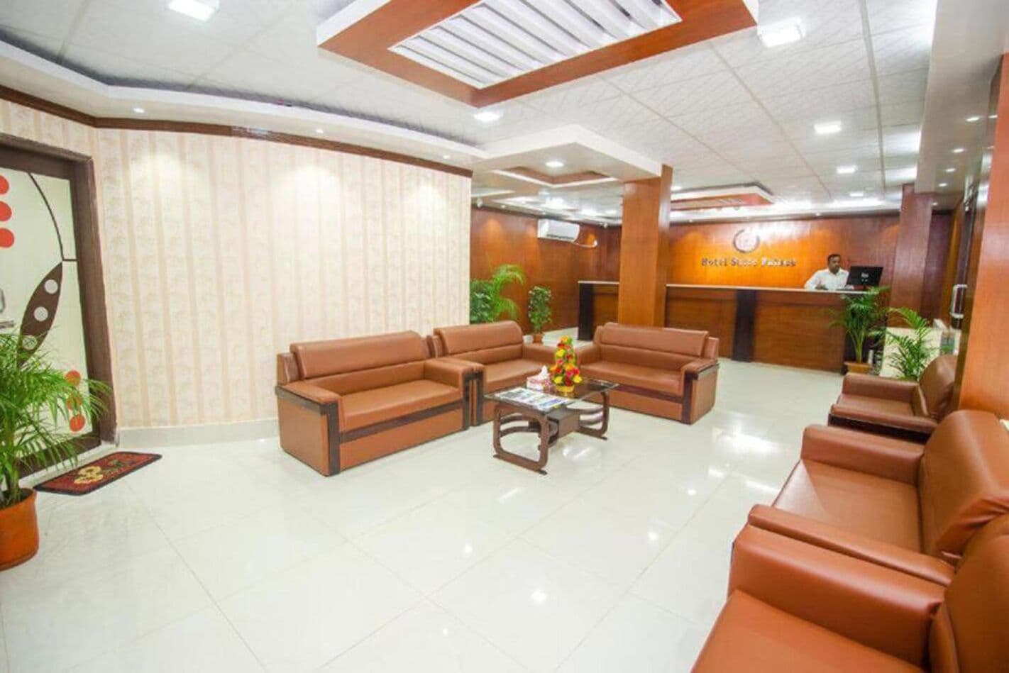 A hotel lobby with leather sofas, a reception desk, and a tiled floor.