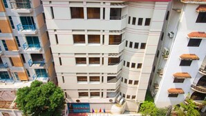 A multi-story building with balconies, a gated entrance, and a flag display. - Hotel Sweet Place (Dhaka)