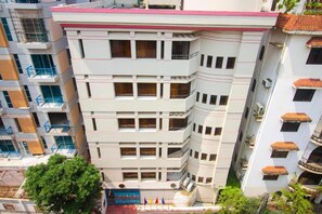 A multi-story building with balconies, a gated entrance, and a flag display. - Hotel Sweet Place (Dhaka)