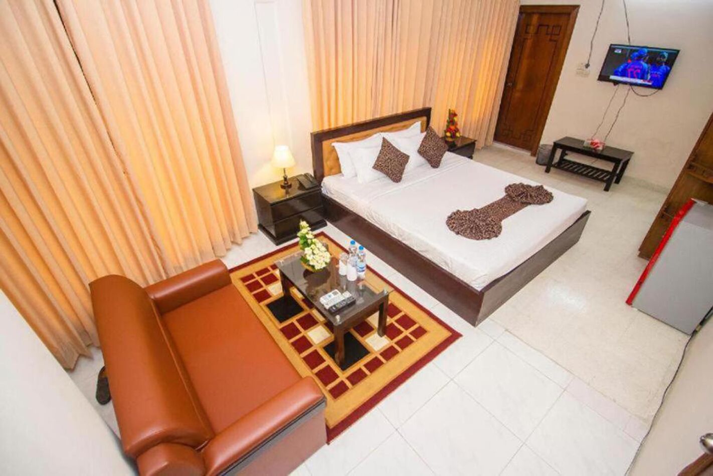 A hotel room with a bed, a sofa, a TV, and a desk with a lamp.