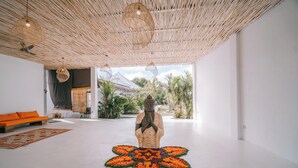 Una habitación con una gran estatua de Buda, techo tejido y un sofá moderno.