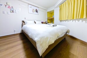 A neatly made bed with white bedding, a wooden headboard, and a yellow curtain on the window. - Ikebukuro 5 Min by Train | 18㎡ for 2 | Double Bed, Kitchen | Fast Wi-Fi (板橋区)